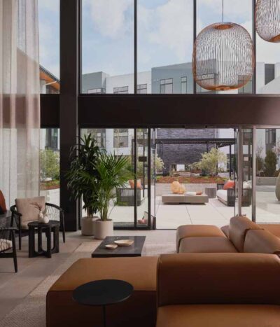 A modern, inviting lounge are with floor-to-ceiling windows at The Apartments Collection at Bay Meadows